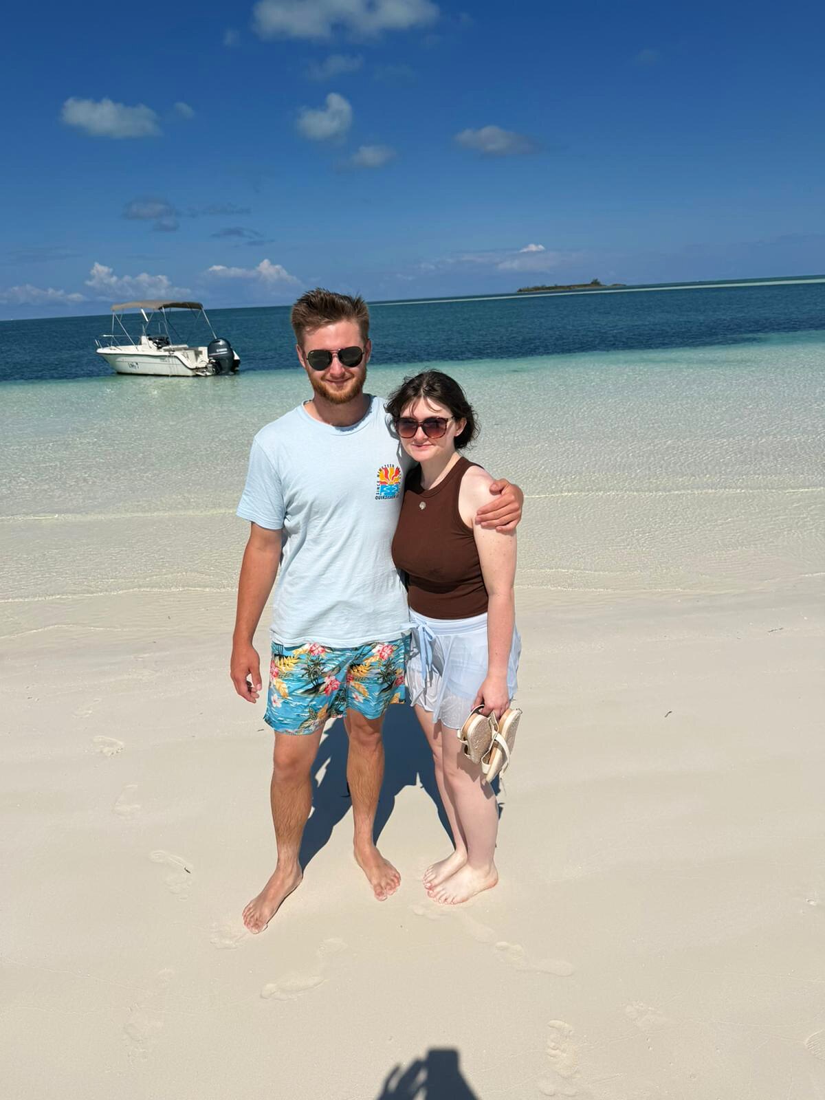A couple standing on a shallow sandbar in calm clear water off Eleuthera.